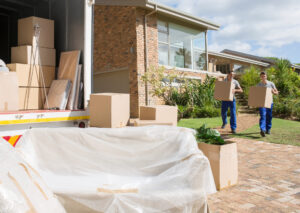 Movers carrying cardboard boxes from house to moving van.