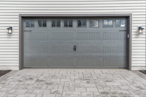 Gray two single car garage door framed with architectural stone to add accent, with transom light windows divided by muntins grills.