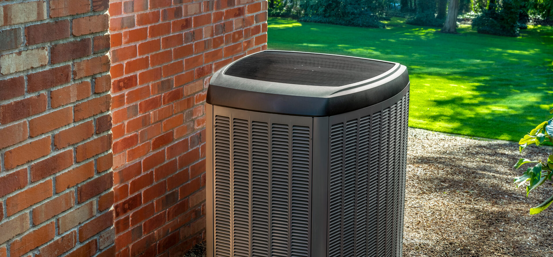 Outdoor air conditioning unit beside a red brick wall.
