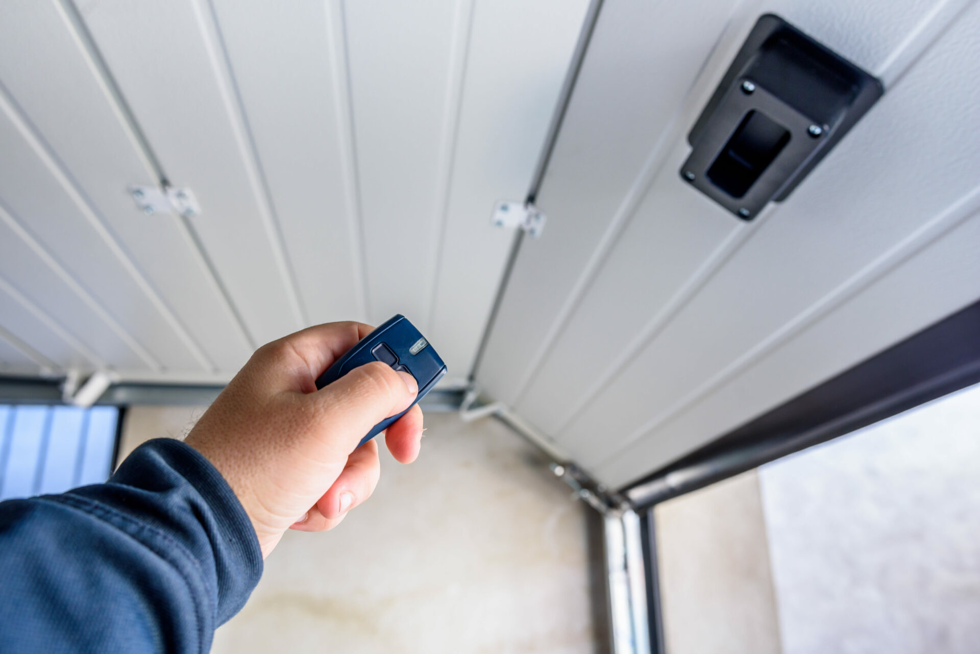 Hand using a remote control for closing and opening garage door.
