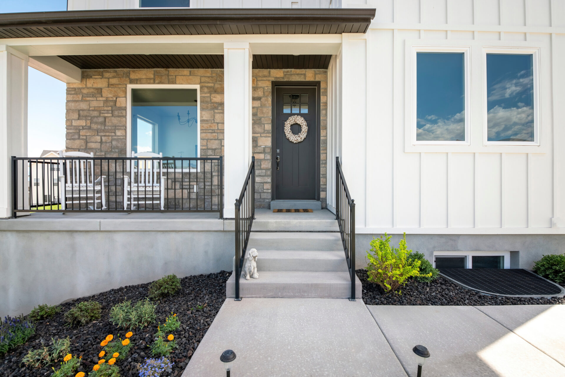 Facade of a house with stone veneer and white board and batten sidings.