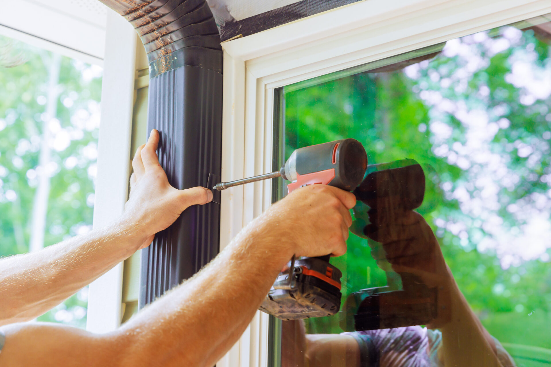 Handyman is assembling gutter pipe on a roof.